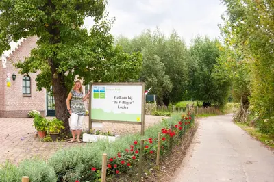 a woman standing next to a sign next to a garden at De Willigen Logies in Vreeland
