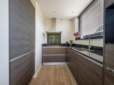 a kitchen with wooden cabinets and a fish tank at Holiday home with sauna in Egmond aan den Hoef