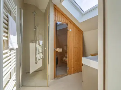 a bathroom with a glass shower and a skylight at Holiday home with sauna in Egmond aan den Hoef