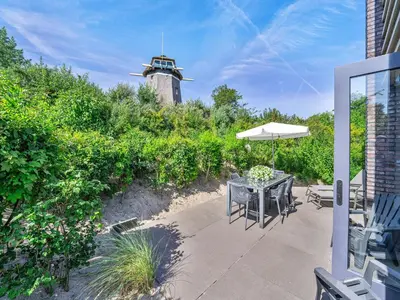 a patio with a table and an umbrella and a lighthouse at Holiday home with sauna in Egmond aan den Hoef