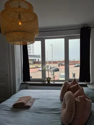 a bedroom with a bed with pillows and a large window at Evy's place in Zandvoort