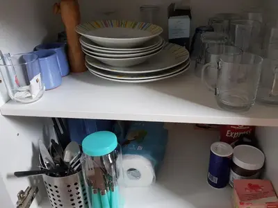 a white shelf with plates and dishes on it at Evy's place in Zandvoort