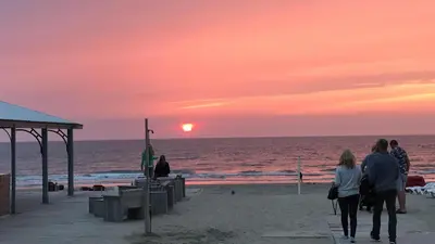a group of people walking on the beach at sunset at Evy's place in Zandvoort