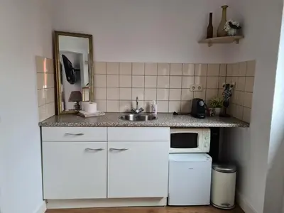 a white kitchen with a sink and a microwave at Evy's place in Zandvoort
