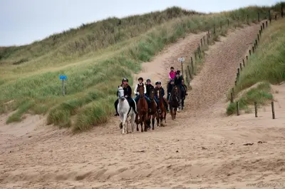 a group of people riding horses on a beach at Vrijstaande blokhut in Egmond-Binnen