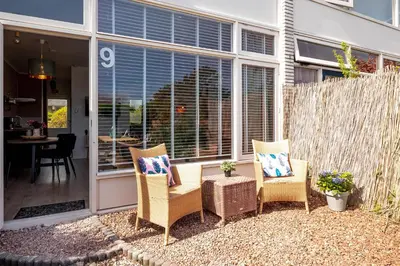 a patio with wicker chairs and a table at Amsterdam Beach Apartment 9, Private Garden in Zandvoort