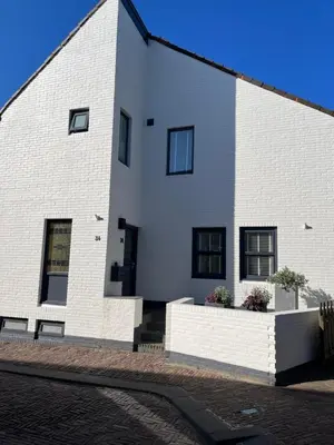 a white building with black windows on a street at Appartement Kwaak in Zandvoort