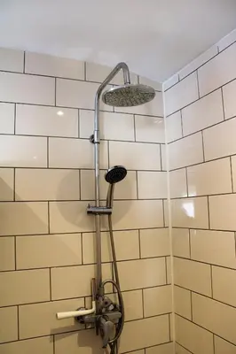 a shower head in a bathroom with white tiles at Appartement Kwaak in Zandvoort