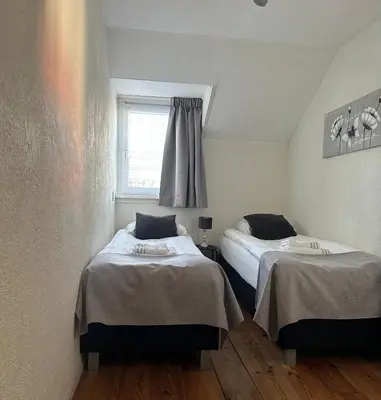 two beds in a small room with a window at Appartement Kwaak in Zandvoort