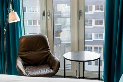a leather chair and a table in front of a window at Motel One Amsterdam-Waterlooplein in Amsterdam