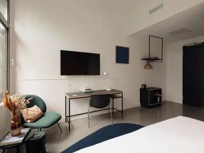 a bedroom with a desk and a tv on the wall at Conscious Hotel Westerpark in Amsterdam