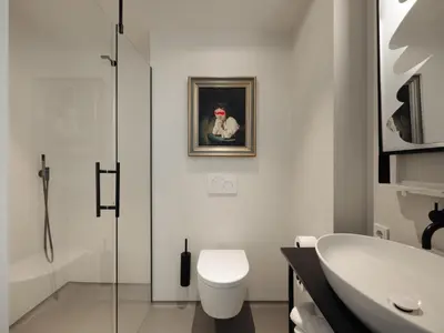 a bathroom with a toilet and a painting of a clown at Conscious Hotel Westerpark in Amsterdam