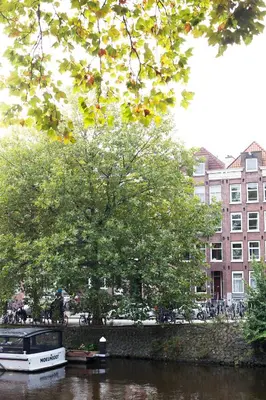 a boat in a river with a tree and buildings at Boutique B&B Nassau in Amsterdam