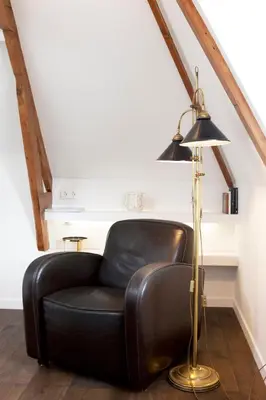 a black leather chair sitting next to a floor lamp at Boutique B&B Nassau in Amsterdam