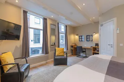 a bedroom with a bed and two chairs and a desk at ExLibris Boutique Hotel in Leiden
