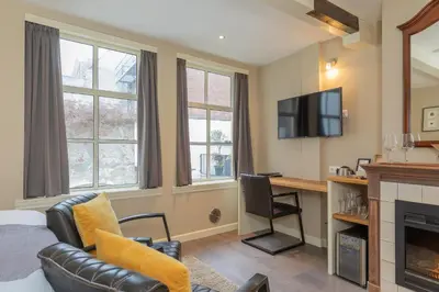 a living room with a bed a desk and a tv at ExLibris Boutique Hotel in Leiden