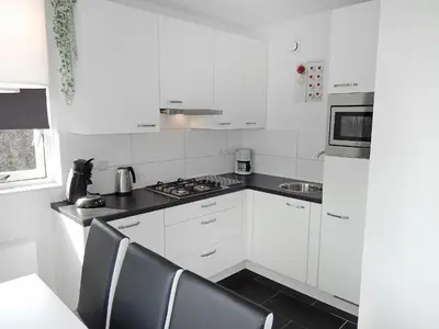 a kitchen with white cabinets and a stove top oven at Holiday Home Plevier Comfort-2 by Interhome in Noordwijk