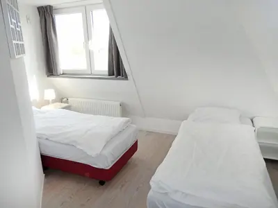 two beds in a small room with a window at Holiday Home Plevier Comfort-2 by Interhome in Noordwijk