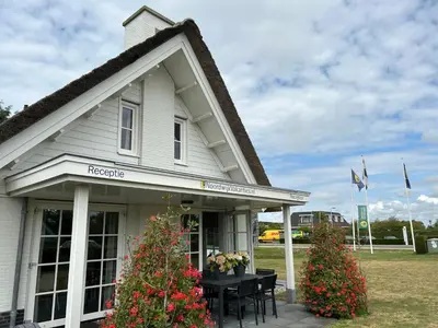 a white house with a table and flowers in front of it at Holiday Home Plevier Comfort-2 by Interhome in Noordwijk