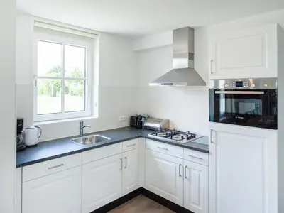 a kitchen with white cabinets and a sink and a window at Holiday Home Alk 8-2 by Interhome in Noordwijkerhout