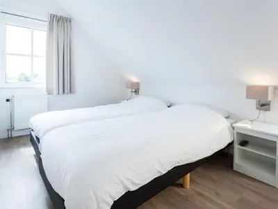 two beds in a white room with a window at Holiday Home Alk 8-2 by Interhome in Noordwijkerhout