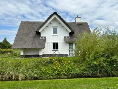 a white house with a gray roof on top of a field at Holiday Home Alk 8-2 by Interhome in Noordwijkerhout