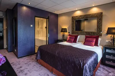 a bedroom with a large bed and a mirror at Hotel Sebastians in Amsterdam