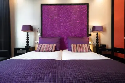 a bedroom with a purple bed with two pillows at Hotel Sebastians in Amsterdam