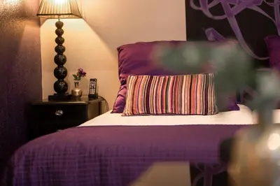 a bedroom with a purple bed with a pillow and a lamp at Hotel Sebastians in Amsterdam