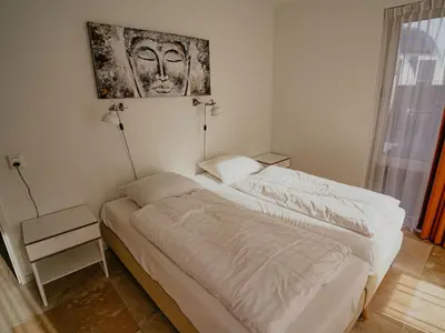 a bedroom with two beds and a painting on the wall at Apartment De Zeeparel by Interhome in Egmond aan Zee