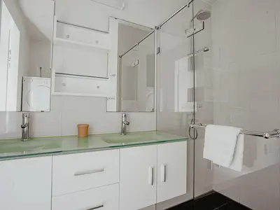 a bathroom with white cabinets and a glass shower at Apartment De Zeeparel by Interhome in Egmond aan Zee