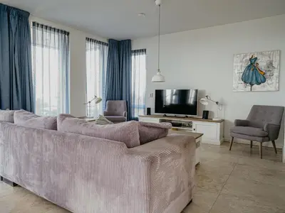 a living room with a couch and a tv at Apartment De Zeeparel by Interhome in Egmond aan Zee