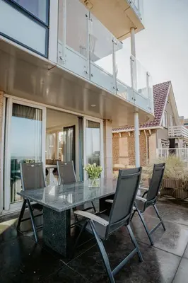 a table and chairs on a patio with a balcony at Apartment De Zeeparel by Interhome in Egmond aan Zee