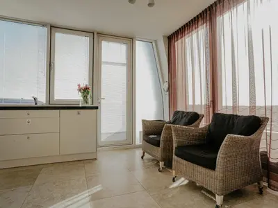 a living room with two chairs and windows at Apartment De Zeeparel by Interhome in Egmond aan Zee