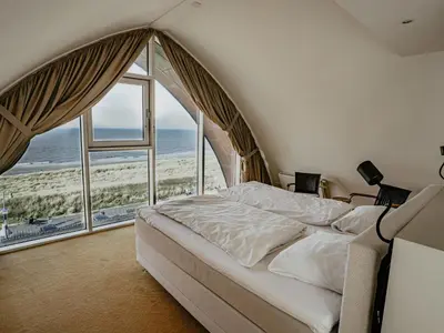 a bedroom with a large bed and a large window at Apartment De Zeeparel by Interhome in Egmond aan Zee
