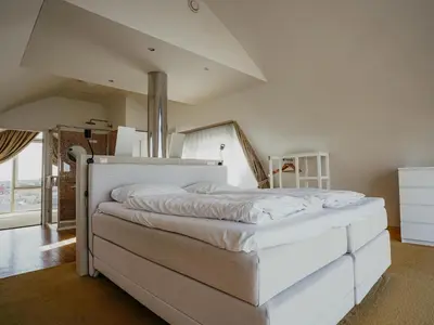 a bedroom with a large white bed in a room at Apartment in Egmond with Sea Views in Egmond aan Zee