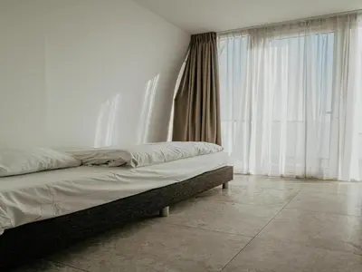 a bed in a room with white walls and windows at Apartment in Egmond with Sea Views in Egmond aan Zee