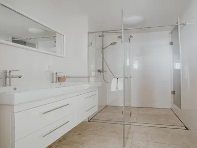 a white bathroom with a shower and a sink at Apartment in Egmond with Sea Views in Egmond aan Zee