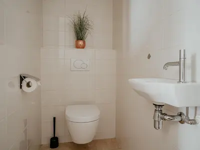 a white bathroom with a toilet and a sink at Apartment in Egmond with Sea Views in Egmond aan Zee