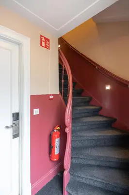 a fire extinguisher is sitting on the wall next to a staircase at Numa Amsterdam Helmers in Amsterdam
