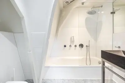 a white bathroom with a shower and a tub at Numa Amsterdam Helmers in Amsterdam