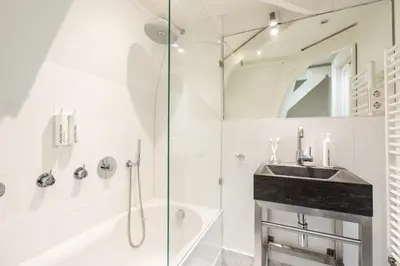 a white bathroom with a sink and a shower at Numa Amsterdam Helmers in Amsterdam