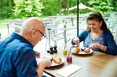 a man and a woman sitting at a table eating food at Hotel Kontakt der Kontinenten in Soesterberg