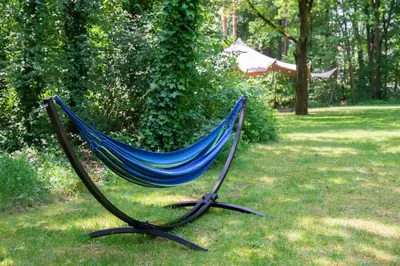 a blue hammock sitting on the grass in a yard at Hotel Kontakt der Kontinenten in Soesterberg