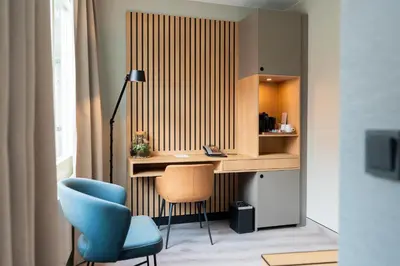 a room with a desk and a blue chair at Hotel Kontakt der Kontinenten in Soesterberg