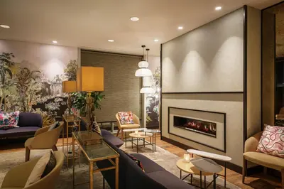 a lobby with a fireplace and couches and chairs at Monet Garden Hotel Amsterdam in Amsterdam
