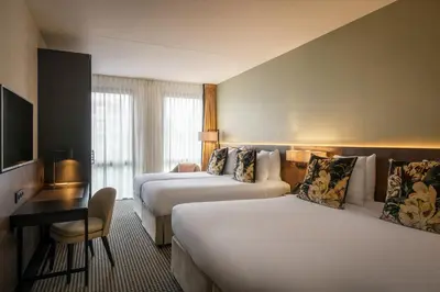 a hotel room with two beds and a desk at Monet Garden Hotel Amsterdam in Amsterdam