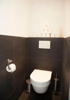 a bathroom with a white toilet in a black wall at hip & stylish apartment in center, near trainstation, 15 min walk in Amsterdam