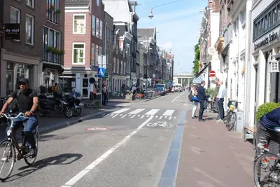 a man riding a bike down a city street at hip & stylish apartment in center, near trainstation, 15 min walk in Amsterdam
