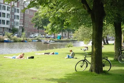 a group of people laying on the grass near a river at hip & stylish apartment in center, near trainstation, 15 min walk in Amsterdam